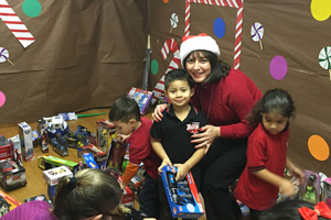 Texas Southmost College Vice President of Instruction, Dr. Marti Flores, distributes toys to Reynaldo Longoria Elementary School students on Dec. 16, 2015, that were collected during TSC’s Third Annual Angel Tree Toy Drive.